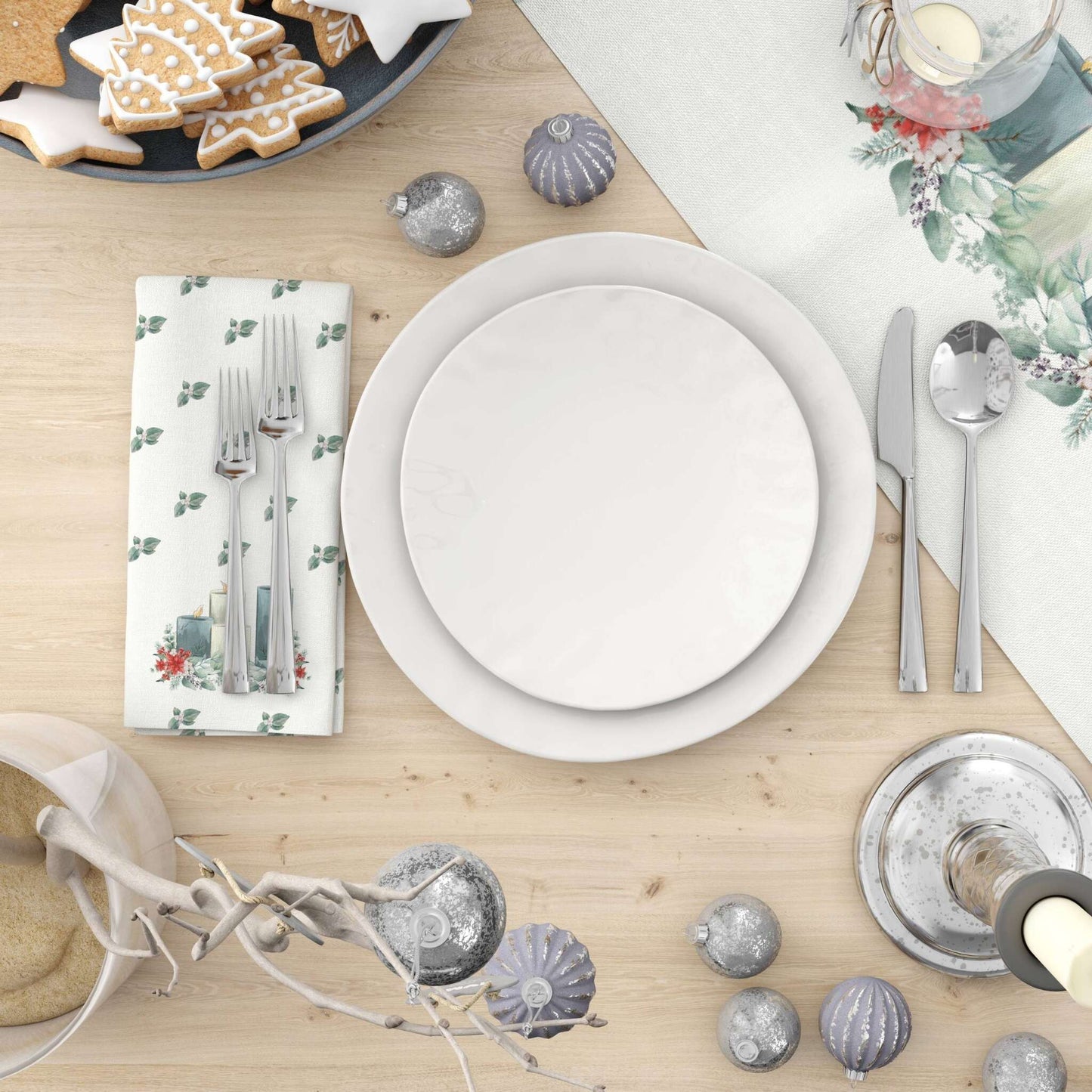 A festive holiday table set with a plate, silverware, and a Christmas-themed napkin and runner. 